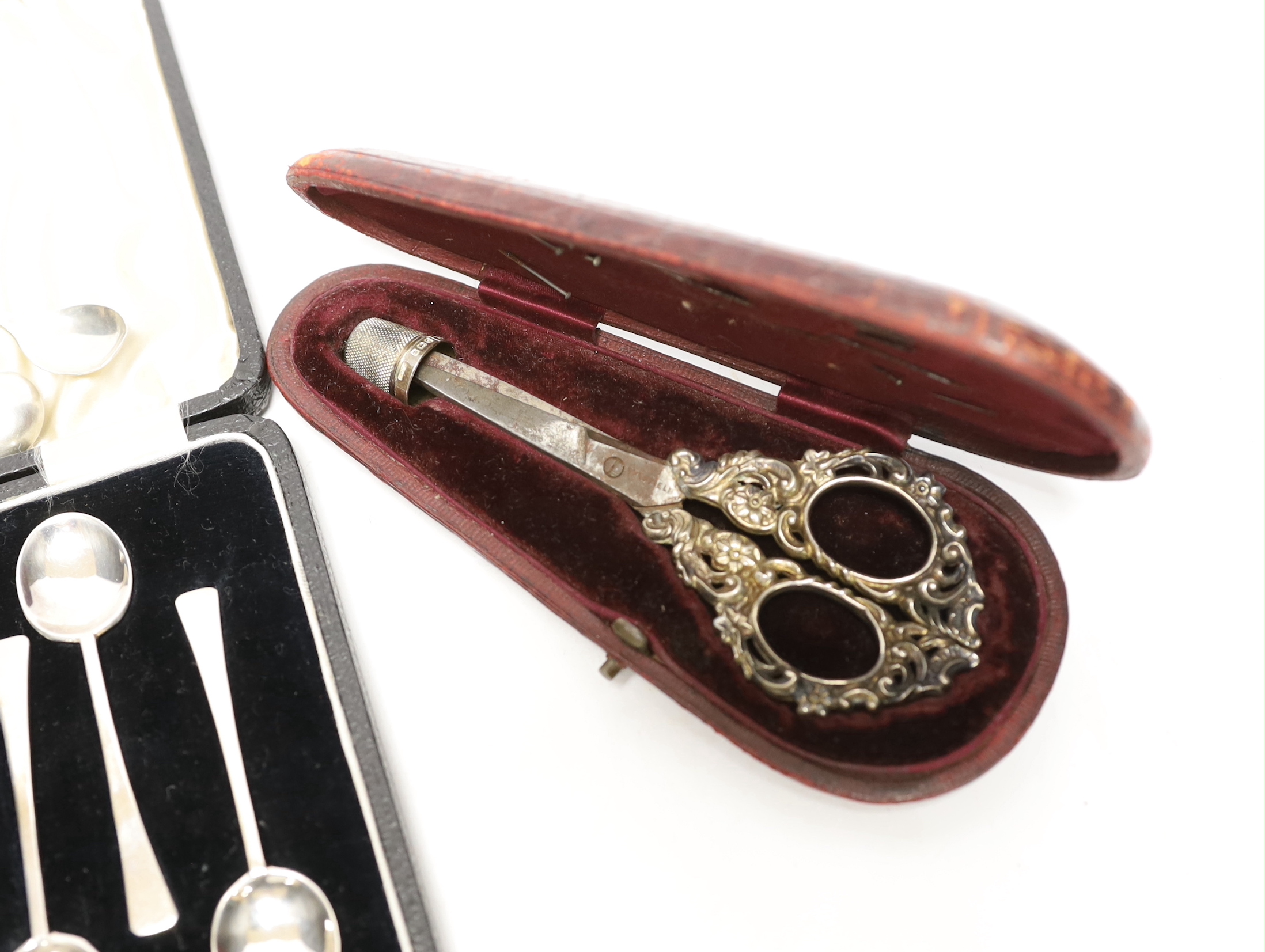 A cased pair of late Victorian repousse silver handled scissors and later silver thimble, a silver mounted photograph frame, cased set of six silver coffee spoons, bookmark, penknife and two condiment spoons.